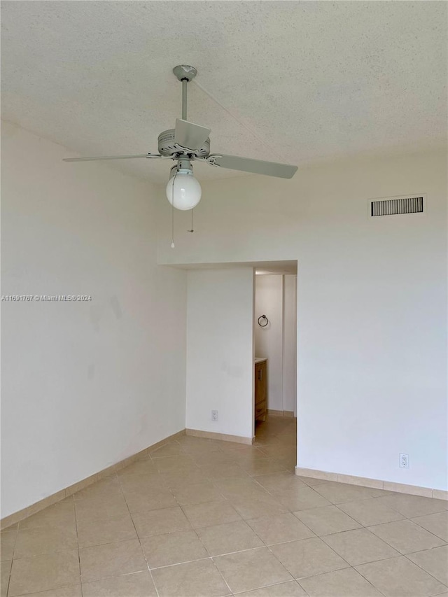 empty room featuring ceiling fan, light tile patterned floors, and a textured ceiling