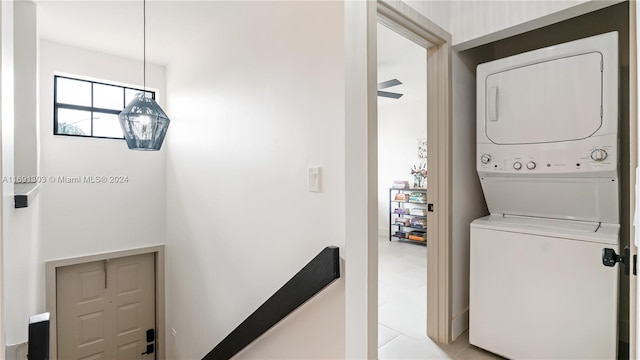 laundry room featuring stacked washer / drying machine, ceiling fan, and light tile patterned flooring