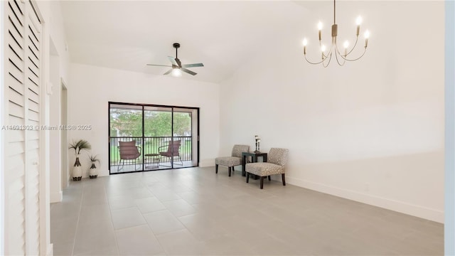 living area featuring ceiling fan with notable chandelier, a high ceiling, and baseboards