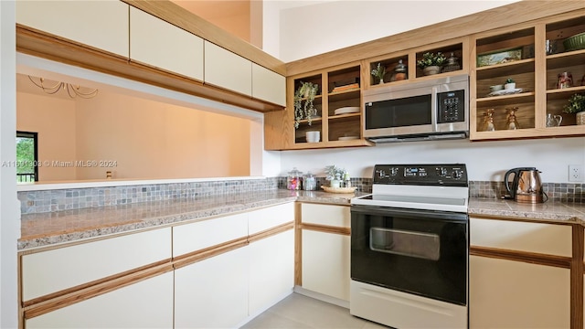 kitchen with white cabinetry, light tile patterned floors, and electric range