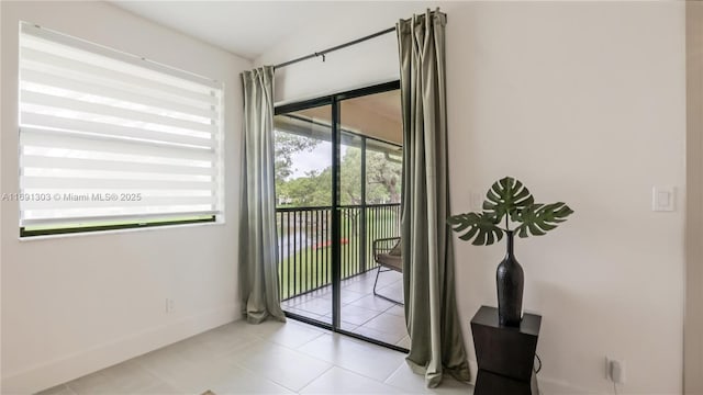 doorway with baseboards and tile patterned floors