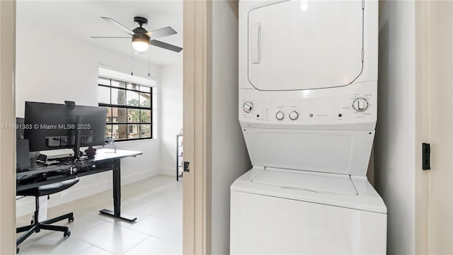 washroom featuring stacked washer and dryer, a ceiling fan, laundry area, baseboards, and tile patterned floors