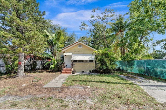 view of front of property with entry steps, a front yard, and fence