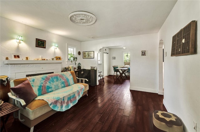 living room featuring arched walkways, baseboards, and wood-type flooring