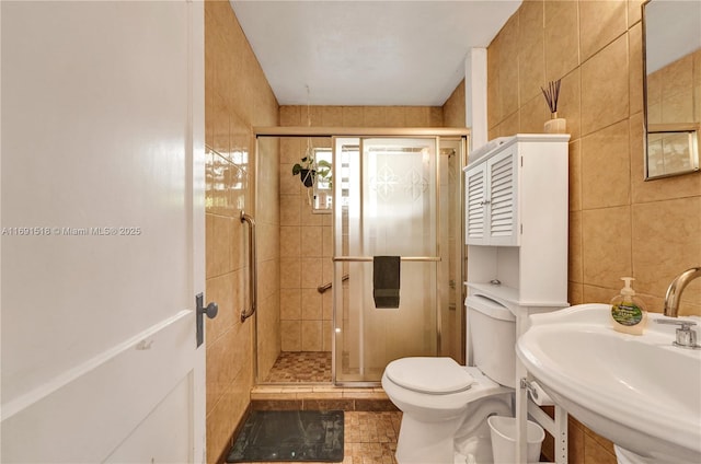 full bath with a sink, toilet, tile walls, and a shower stall