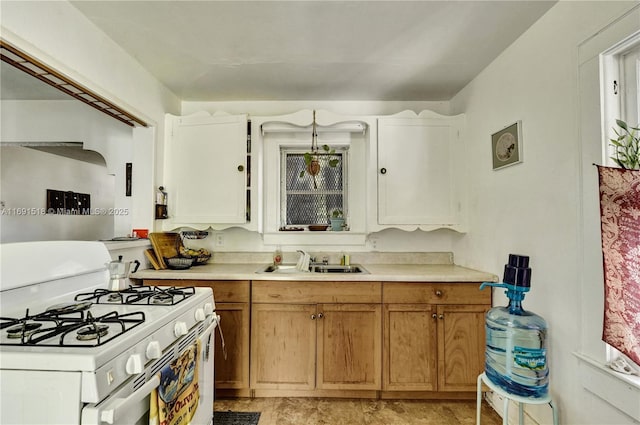 kitchen featuring light countertops, brown cabinets, white gas range, and a sink