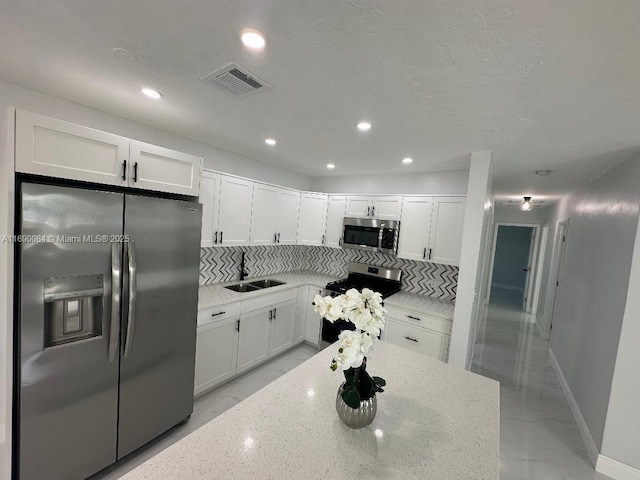 kitchen with white cabinetry, sink, stainless steel appliances, and light stone countertops