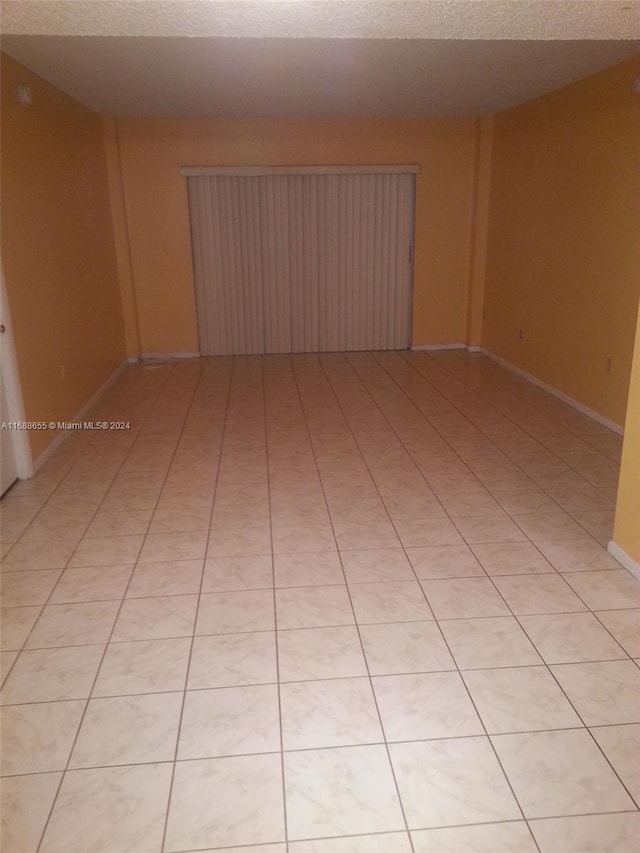 unfurnished room with light tile patterned flooring and a textured ceiling