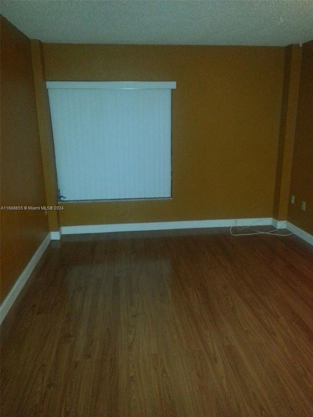 empty room featuring dark wood-type flooring and a textured ceiling