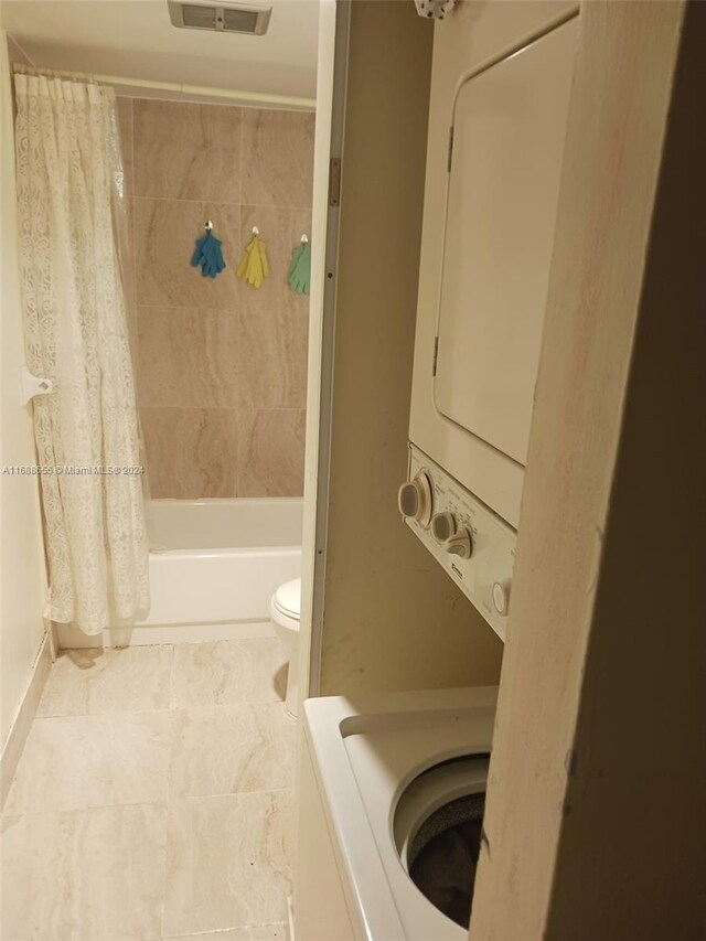 laundry area featuring tile patterned floors and stacked washer / dryer