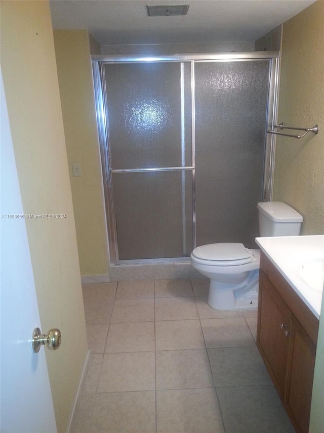 bathroom with vanity, walk in shower, tile patterned floors, and toilet