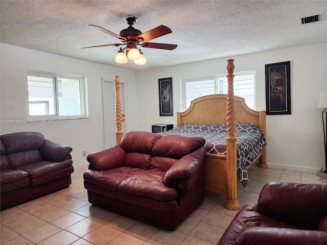 tiled bedroom with ceiling fan and a textured ceiling