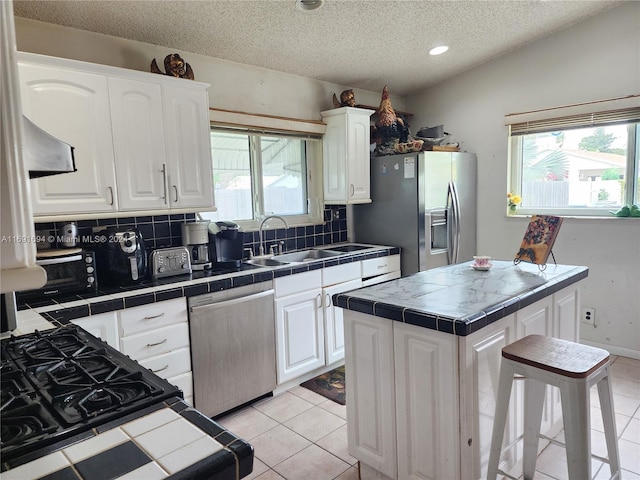 kitchen featuring a wealth of natural light, stainless steel appliances, tile counters, and sink