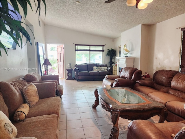 living room featuring lofted ceiling, ceiling fan, light tile patterned floors, and a textured ceiling