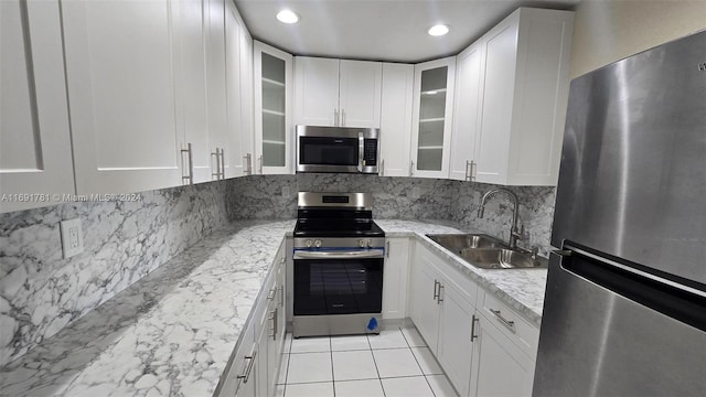 kitchen with white cabinets, appliances with stainless steel finishes, sink, and light stone counters