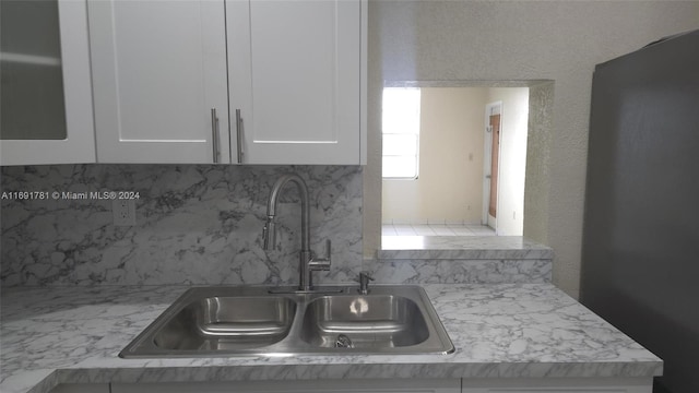 kitchen featuring white cabinets, sink, and light stone counters