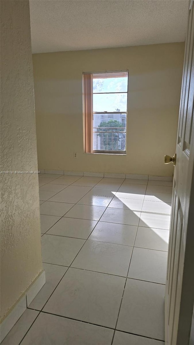 tiled empty room featuring a textured ceiling