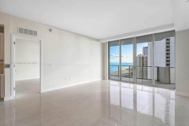 tiled empty room with floor to ceiling windows and a water view