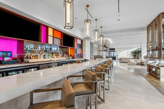 bar featuring light stone counters and hanging light fixtures