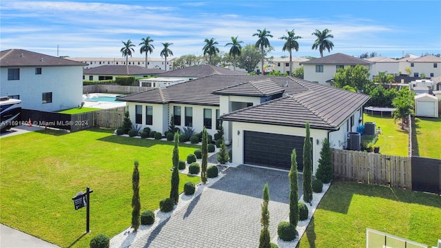 view of front of home featuring cooling unit, a front yard, and a garage