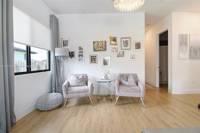 sitting room with light hardwood / wood-style floors and an inviting chandelier