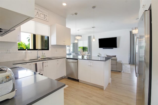 kitchen featuring kitchen peninsula, white cabinetry, plenty of natural light, and appliances with stainless steel finishes