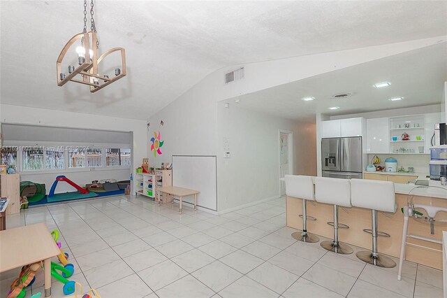 rec room featuring light tile patterned flooring, a textured ceiling, vaulted ceiling, and a notable chandelier