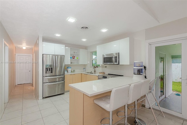 kitchen with stainless steel appliances, white cabinetry, sink, and kitchen peninsula