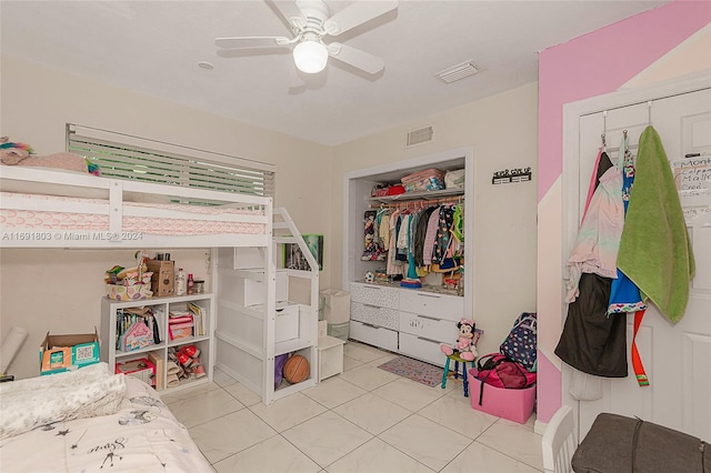 tiled bedroom featuring ceiling fan and a closet