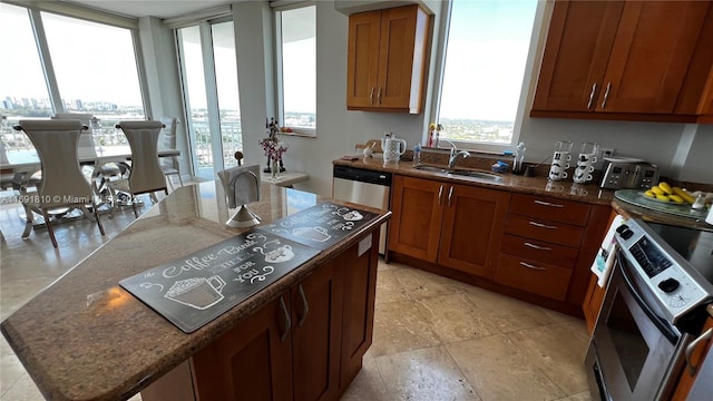 kitchen with sink, stainless steel appliances, dark stone counters, and a kitchen island