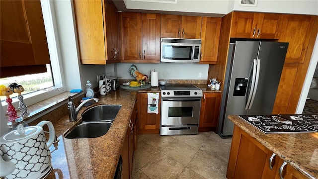 kitchen featuring dark stone countertops, sink, and stainless steel appliances