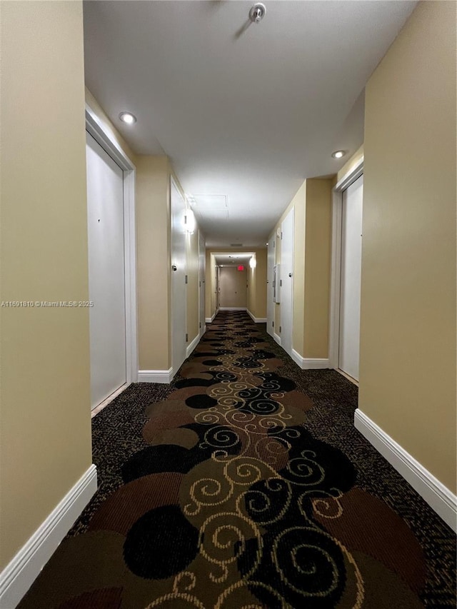 hallway with dark colored carpet