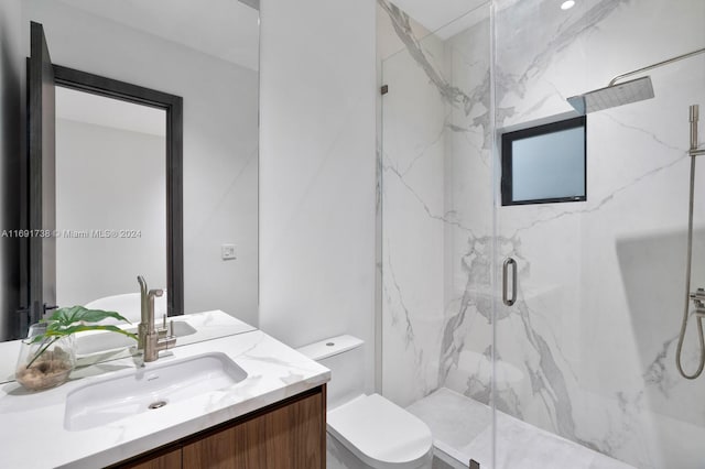 bathroom featuring toilet, vanity, and a shower with shower door