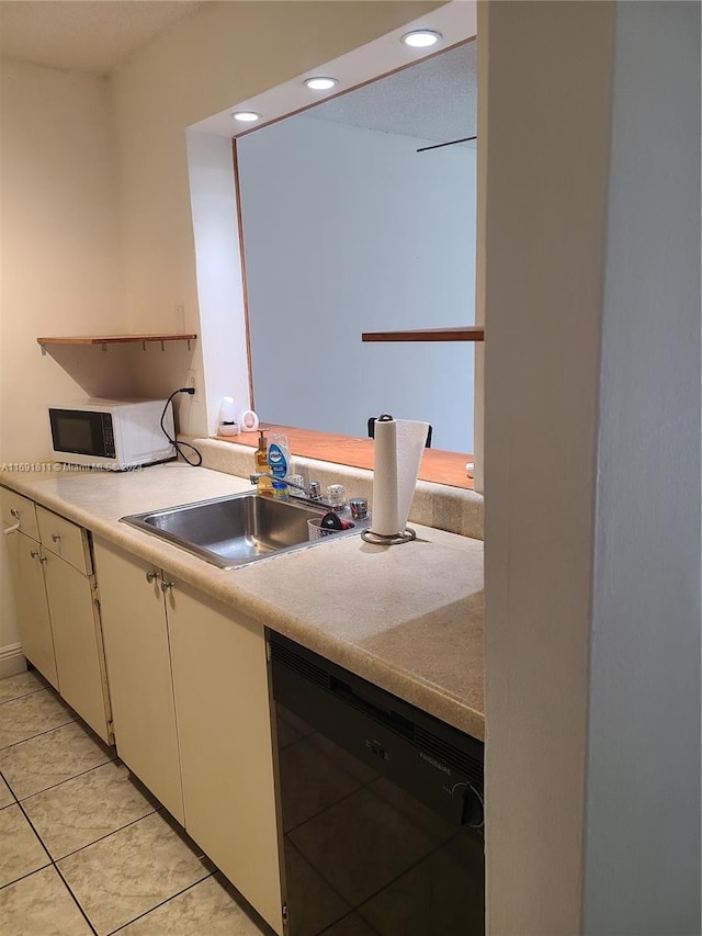 kitchen featuring light tile patterned floors, black dishwasher, white cabinetry, and sink