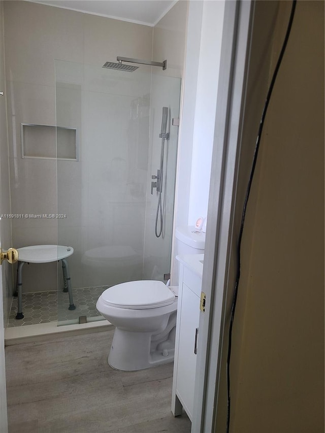 bathroom with walk in shower, hardwood / wood-style floors, vanity, and toilet