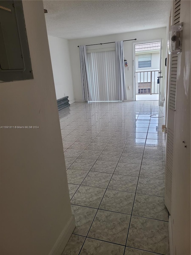 empty room featuring light tile patterned floors, a textured ceiling, and electric panel