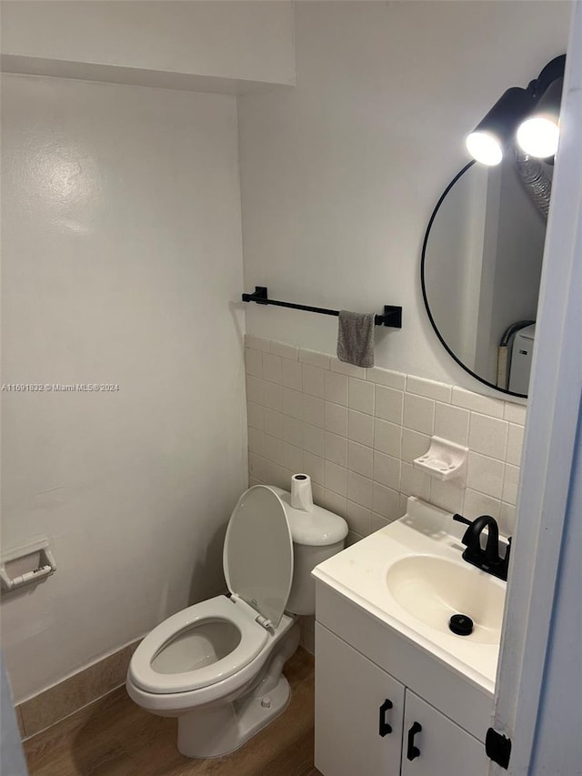 bathroom with wood-type flooring, vanity, toilet, and tile walls