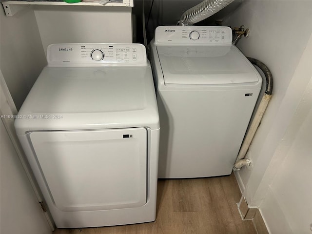 washroom with light wood-type flooring and washing machine and dryer