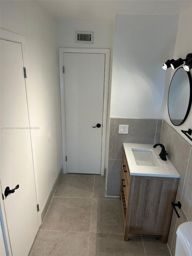 bathroom with tile patterned flooring, vanity, toilet, and tile walls