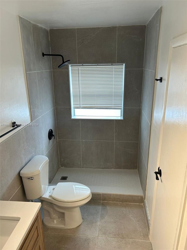 bathroom with toilet, vanity, tile patterned floors, and a tile shower