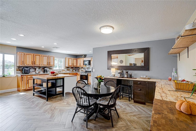 dining space with a wealth of natural light, a textured ceiling, and light parquet floors