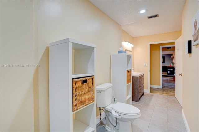 bathroom featuring toilet, vanity, a textured ceiling, and tile patterned floors