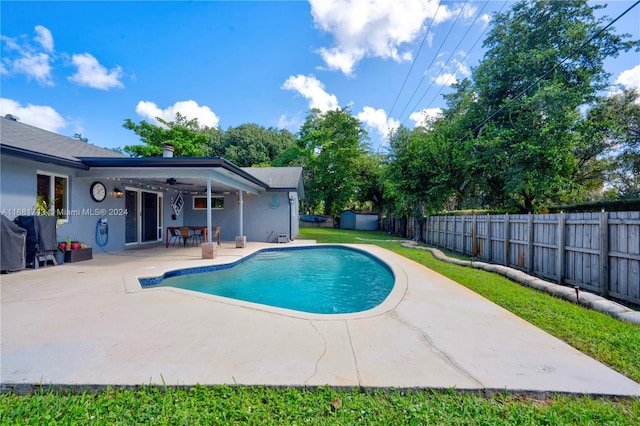 view of pool with a shed, ceiling fan, and a patio