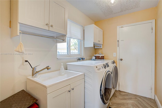 washroom with washing machine and clothes dryer, cabinets, a textured ceiling, and light parquet floors