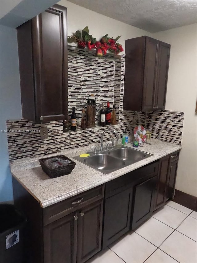 kitchen featuring dark brown cabinetry, sink, and tasteful backsplash