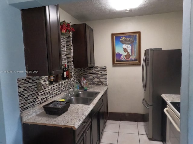 kitchen featuring tasteful backsplash, a textured ceiling, light tile patterned floors, sink, and white stove