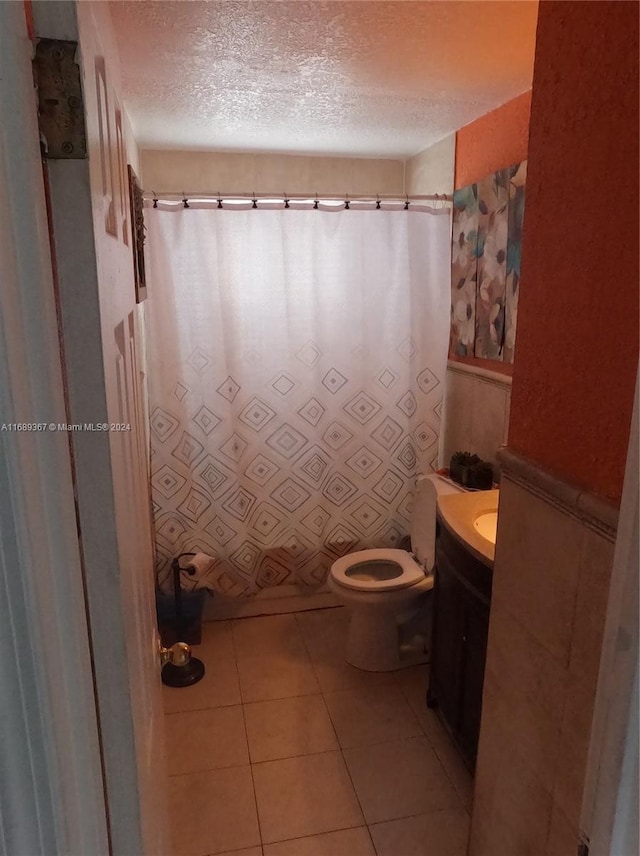 bathroom featuring a textured ceiling, vanity, tile patterned floors, and toilet