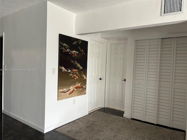 hall featuring a textured ceiling and dark tile patterned floors