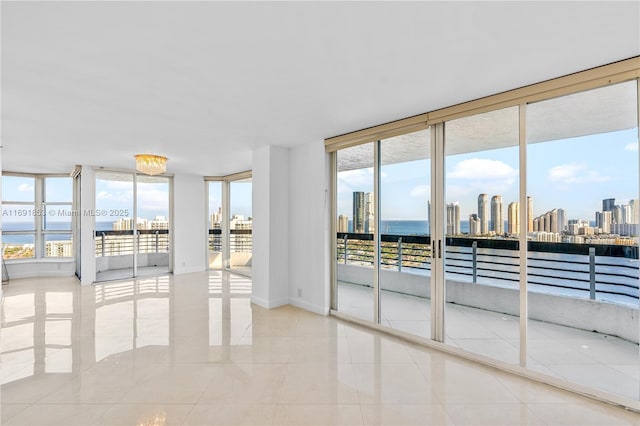 unfurnished room featuring floor to ceiling windows, a water view, and light tile patterned floors