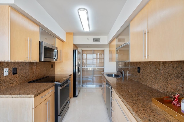 kitchen with stone counters, light brown cabinets, backsplash, and appliances with stainless steel finishes